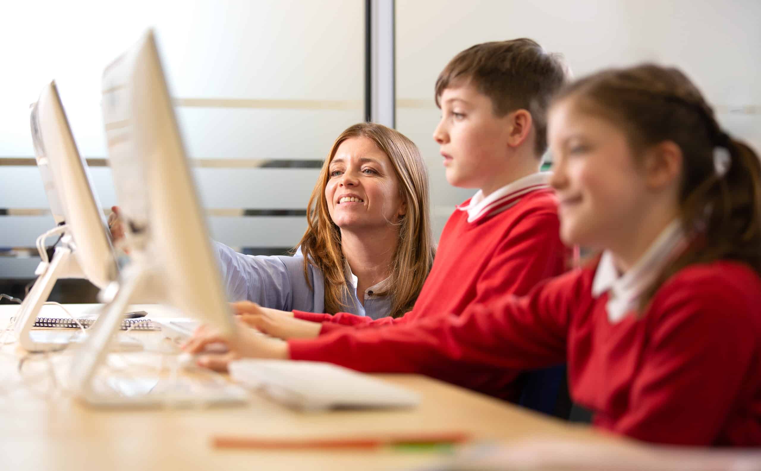 Children using computer with teacher